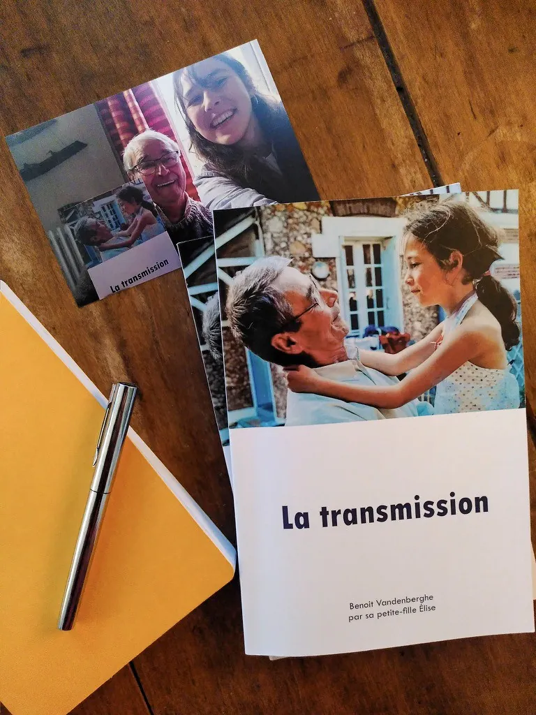La transmission, biographie de Benoit Vandenberghe écrite par sa petite-fille Élise, posée sur une table avec un carnet et un stylo